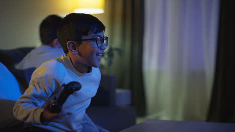 Two-Young-Boys-At-Home-Having-Fun-Playing-With-Computer-Games-Console-On-TV-Fighting-Over-Controllers-Late-At-Night-4